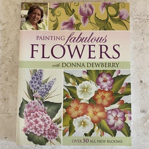 May include: A book titled "Painting Fabulous Flowers" by Donna Dewberry. The cover features floral illustrations in shades of pink, purple, orange, and white. The book includes the text "Over 50 All New Blooms" and a photo of the author.