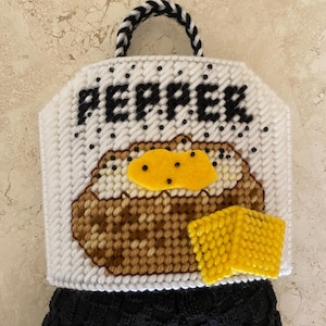 Puede incluir: Toallero de cocina blanco cosido a mano con asa en blanco y negro. El diseño presenta una patata al horno con un cuadrado de queso amarillo y la palabra "PEPPER" en negro.