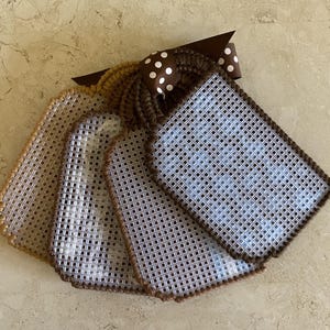 Pu&ograve; includere: Cinque etichette in tela plastica marrone e bianca con bordatura marrone. Le etichette sono vuote e pronte per essere ricamate. Un nastro marrone con pois bianchi &egrave; attaccato alla parte superiore delle etichette.