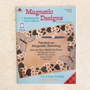 May include: A instructional booklet titled Magnetic Designs by Pamela Bialas featuring a light blue cover with text and illustrations of painted butterflies and flowers. The booklet provides guidance on painting on magnetic sheeting for metal surfaces.