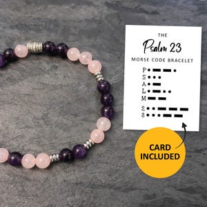 May include: A beaded bracelet with alternating pink and purple gemstones, connected by silver-colored metal beads. A card with the text "THE Psalm 23 MORSE CODE BRACELET" and Morse code symbols is included. The card is accompanied by a yellow circle that says "CARD INCLUDED".