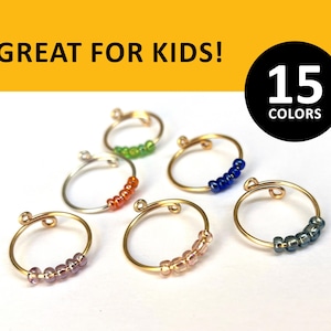 May include: Six gold rings with different colored beads. The rings are all the same size and have a small loop on one side. The text "15 COLORS" is visible in the image.