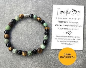 May include: A black, green and brown beaded bracelet with a silver clasp. The bracelet comes with a card that reads "I am the Storm. Courage Bracelet. Tiger's Eye for courage. African Turquoise for growth. Black Onyx for strength. "Fate whispers to the warrior, 'You cannot withstand the storm.' The warrior whispers back, 'I am the storm." Card Included!"