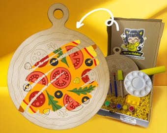 May include: A wooden pizza-shaped cutting board with a painted pizza design. The image also shows a kit with paint, brushes, and a palette. The box has a sticker that says "Hi! I'm Maloha!"