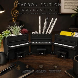 May include: Three black piano-shaped containers from the Carbon Edition Collection. One functions as a planter with succulents, one as a pen holder containing patterned pencils, and one as a business card holder. Each features a keyboard and bench.
