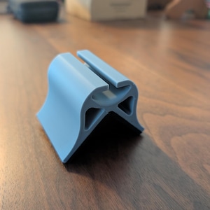 May include: A light blue plastic corner protector with a rounded edge and a slot for a cable. The protector is designed to protect corners from damage.