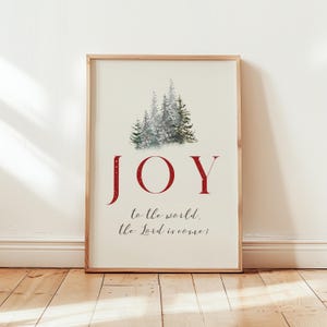 K&ouml;nnte beinhalten: Gerahmter Kunstdruck mit hellem Hintergrund. Das Wort "JOY" steht in gro&szlig;en, roten Buchstaben. Darunter steht der Text "to the world, the Lord is come!" Oben befindet sich ein Aquarellbild von Nadelb&auml;umen.