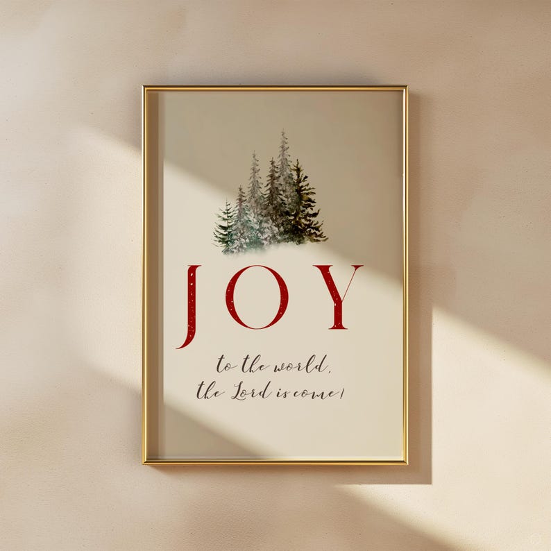 K&ouml;nnte beinhalten: Gerahmter Kunstdruck mit goldenem Rahmen. Der Druck zeigt eine Aquarellillustration von immergr&uuml;nen B&auml;umen &uuml;ber dem roten Wort "JOY". Darunter steht der Text "to the world, the Lord is come!"