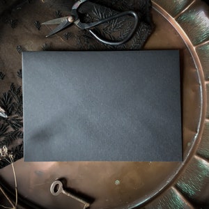 May include: A black card blank on a copper tray with a black lace fabric and a pair of antique scissors.