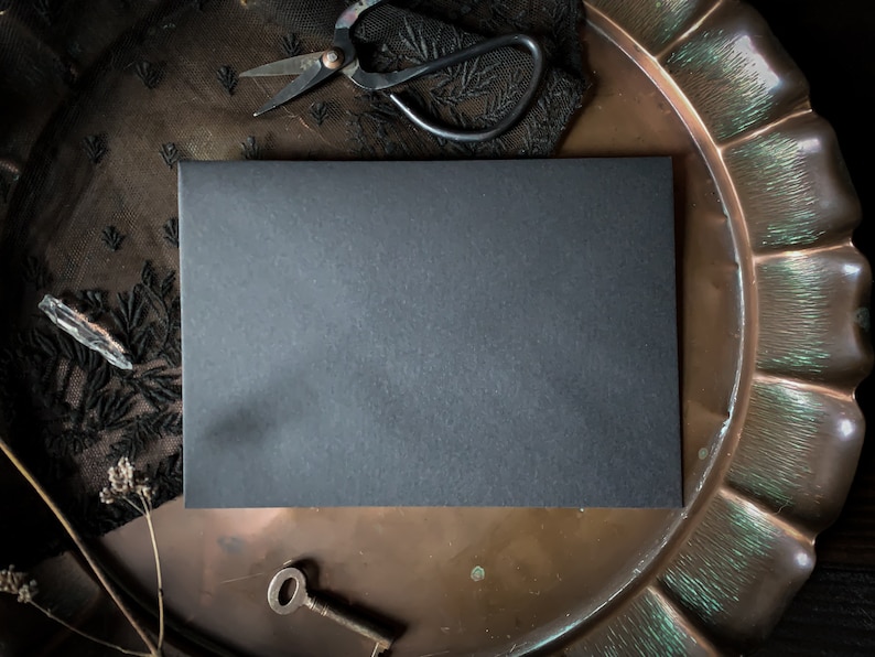 May include: A black card blank on a copper tray with a black lace fabric and a pair of antique scissors.