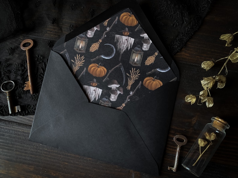 May include: A black envelope with a Halloween-themed paper insert. The insert features a repeating pattern of pumpkins, lanterns, and other spooky imagery.