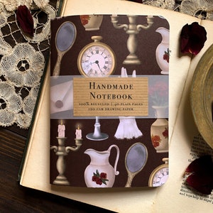 Op de afbeelding: Een bruin handgemaakt notitieboek met een vintage ontwerp met een klok, kaarsen, spiegels en een kan. Het notitieboek is 100% gerecycled en heeft 120 g/m² tekenpapier.