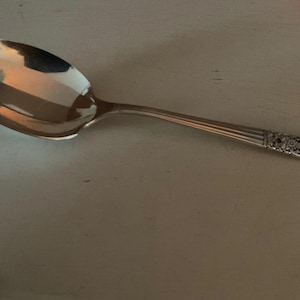 Puede incluir: Una cuchara de plata con un diseño adornado en el mango.