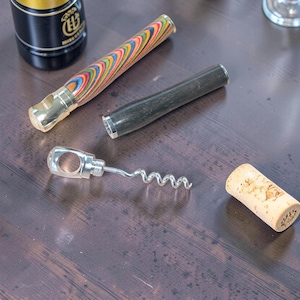 Peut inclure: Un ensemble d'ouvre-bouteilles comprenant un manche à motif rayé multicolore, un manche gris anthracite uni, un tire-bouchon en métal argenté avec une mèche en spirale et un bouchon en liège cylindrique de couleur brun clair naturel.