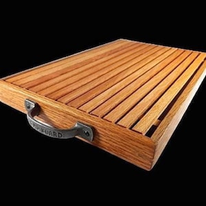 May include: A rectangular wooden serving tray with a slatted top and a dark metal handle. The tray is made of light brown wood and has a handle on one side. The handle is inscribed with the word "BOARD".