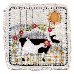 May include: Embroidered artwork depicting a black and white cow standing in a field of green grass with yellow flowers. The cow is surrounded by a vine with red flowers and a yellow sun is shining in the sky.