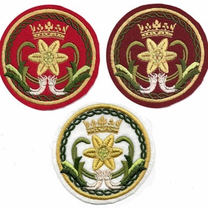 May include: Three embroidered patches with floral and crown designs. The patches feature a central flower with a crown above it, surrounded by a circular border. The patches are in red, maroon, and white with gold, green, and white accents.