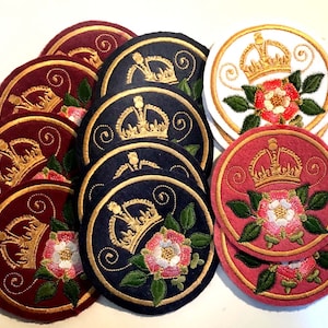 May include: A collection of embroidered patches featuring a gold crown and a white rose on a red, blue, or white background. The patches are circular and have a decorative border.