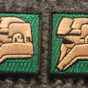 May include: Two green and white embroidered patches featuring a helmet design. The helmet is white with black details and the text "F.C.M." is embroidered on the side.