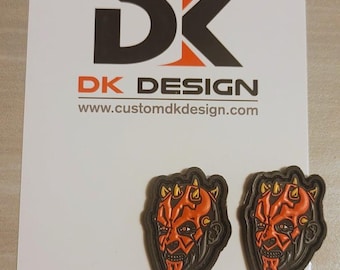 Può includere: Due patch stampati in 3D di colore nero e arancione che raffigurano il volto di Darth Maul di Star Wars. I patch sono su uno sfondo bianco con il testo "DK DESIGN" e "www.customdkdesign.com".