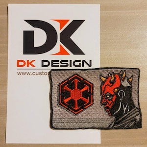 May include: A gray and black embroidered patch with a red symbol and a red and black illustration of Darth Maul's head. The patch has the text "DK DESIGN" and "www.custom".