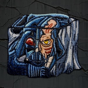 Puede incluir: Parche bordado que representa a Darth Vader, con parte de su rostro y casco visibles. El parche utiliza costuras detalladas en azul, negro, rojo y beige, creando un efecto texturizado y artístico. El parche tiene forma cuadrada.