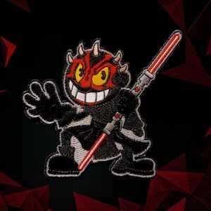 May include: Embroidered patch featuring a cartoon-style character with a red and black face, yellow eyes, and a wide grin. The character is holding a red lightsaber. The patch is black with white stitching and is set against a black background with red geometric shapes.