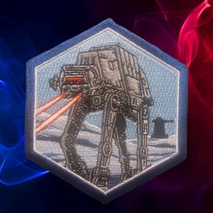 May include: Hexagonal embroidered patch depicting an AT-AT walker firing lasers in a snowy scene. The patch has a light blue border. The AT-AT is grey with red laser beams.