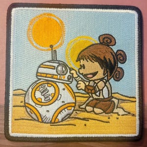May include: A white and orange robot with a round body and a small head is standing next to a cartoon girl with brown hair. The girl is wearing a brown and white outfit. The background is a light blue sky with two yellow suns.
