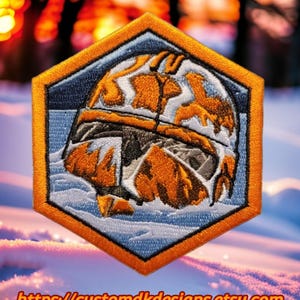 以下が含まれることがあります： 青と白の背景に、六角形の星形戦争クローン・トルーパーのヘルメットが描かれたオレンジと白の刺繍パッチ。パッチは白い縁取りとオレンジ色の輪郭があります。