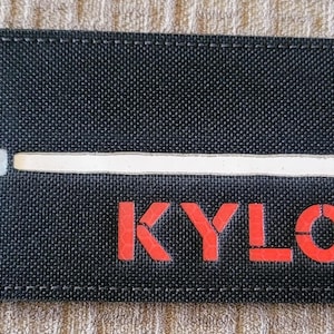 May include: Black fabric patch with a white lightsaber and the text "KYLO REN" in red.
