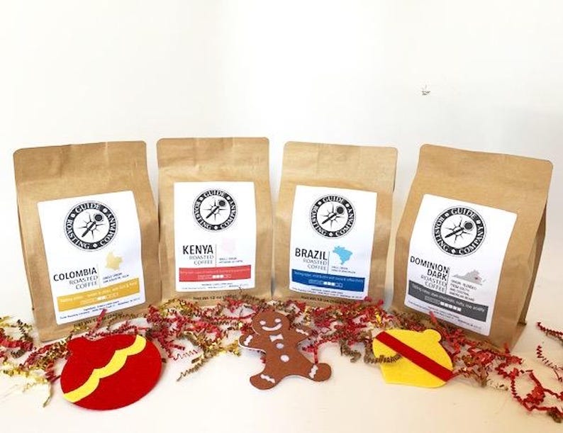 May include: Four bags of coffee beans with festive holiday decorations. The bags are labeled with the origin of the beans: Colombia, Kenya, Brazil, and Dominion Dark.