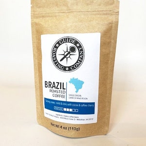 May include: A brown paper bag with a white label that says "Guide Roasting Company" and "Brazil Roasted Coffee". The label also includes a compass logo, a map of Brazil, and tasting notes. The bag contains 4 ounces (113 grams) of coffee.