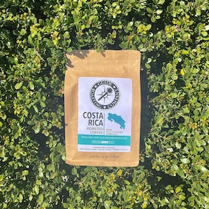 May include: A brown paper bag with a label that says "Costa Rica Roasted Coffee" with a map of Costa Rica and the text "Origin: Various small-crop holders in the TARRAZU region". The label also says "Tasting notes: sweet cocoa with praline & citrus fruit" and "Net Wt 12 oz (340g)".