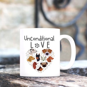 May include: White ceramic coffee mug with a black and brown illustration of dog faces in a heart shape. The text "Unconditional LOVE" is printed on the mug.