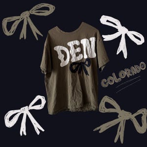May include: An olive green t-shirt with the word "DEN" in white block letters. A black bow is below the text. The word "Colorado" is written in a circle in the lower right corner. White and olive green bows are drawn around the shirt.