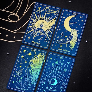 Pode incluir: Quatro cartas de tar&ocirc; com fundos azuis e detalhes em ouro. As cartas s&atilde;o O Sol, A Lua, A Estrela e O Mundo. Cada carta apresenta um design celestial e uma mulher.