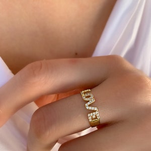 May include: Gold ring with the word "LOVE" spelled out in pave diamonds.