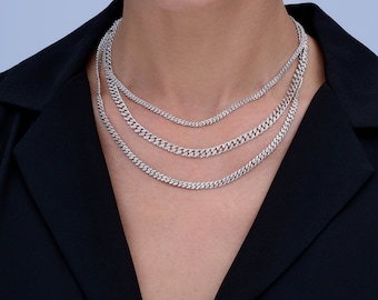 May include: A woman wearing a black shirt with a layered silver chain necklace.