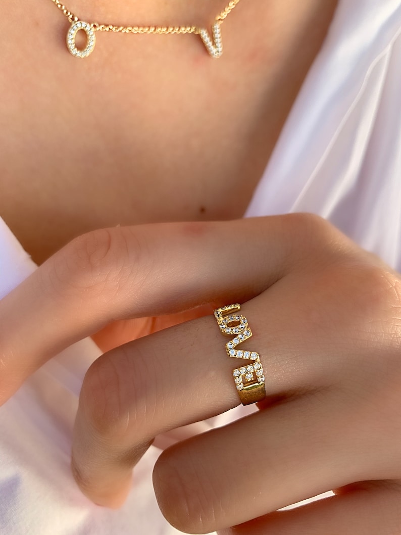 May include: Gold ring with the word "LOVE" spelled out in pave diamonds.