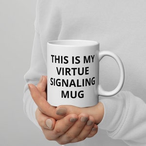 Könnte beinhalten: Eine weiße Keramiktasse mit schwarzem Text, der "This is my virtue signaling mug" lautet.
