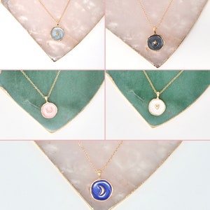 May include: Five gold necklaces with different colored enamel pendants. Each pendant features a different celestial symbol: a crescent moon, a star, a heart, a crescent moon with a star, and a crescent moon.