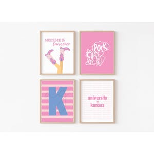 Op de afbeelding: Vier ingelijste prints met roze en witte ontwerpen. Eén print zegt "Meet Me in Lawrence" met illustraties van laarzen. Een andere zegt "Rock Chalk Go KU!" in het wit. De derde heeft een blauwe "K" op roze strepen. De laatste zegt "University of Kansas".