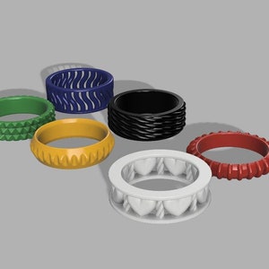 Puede incluir: Seis anillos coloridos con diferentes patrones texturizados. Los anillos son de plástico y están dispuestos en círculo. Los colores de los anillos son verde, amarillo, azul, negro, rojo y blanco.