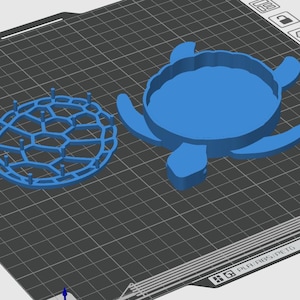 Op de afbeelding: Een blauwe 3D-geprinte schildpadschelpvorm met een aparte basis. De vorm heeft een gedetailleerd ontwerp met een textuur.