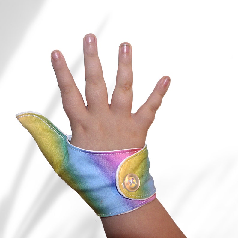 A  fabric thumb guard to help deter thumb-sucking habits.  Suitable for all ages. Features a pastel rainbow design.  Moisture-resistant lining. Choice of fastenings. The Thumb Guard Store.