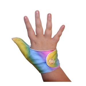 A fabric thumb guard, made by The Thumb Guard Store,  to help stop habits such as thumb-sucking. This guard has a moisture-resistant lining. The outer fabric is a pastel rainbow pattern.  Choice of fastenings available.
