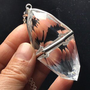 May include: A clear quartz crystal pendant with a silver setting and chain. The crystal is faceted and has a pointed tip.