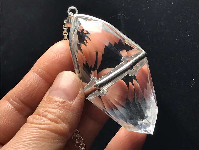 May include: A clear quartz crystal pendant with a silver setting and chain. The crystal is faceted and has a pointed tip.