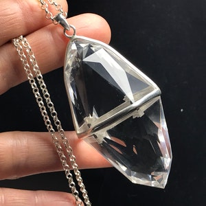 May include: A clear quartz crystal pendant with a silver setting, hanging from a silver chain.